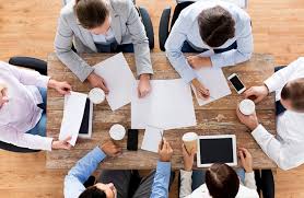 Four people at a table with coffee and ipads