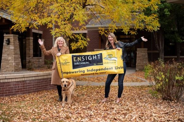 Staff holding Enisight banner with dog underneath